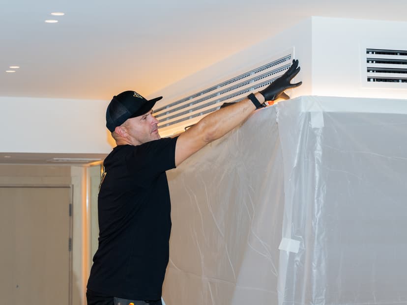 Engineer removing vent grille for duct inspection